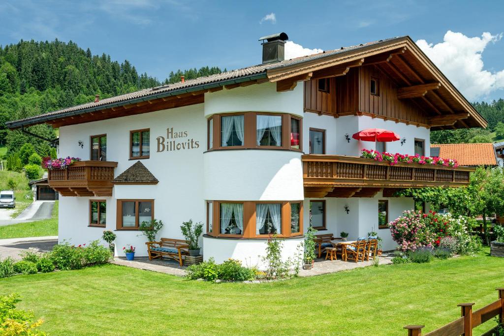 a large white house with wooden balconies at Ferienwohnungen Billovits in Kössen