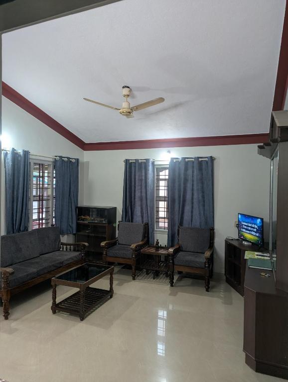 a living room with couches and chairs and a tv at Coorg homes in Madikeri