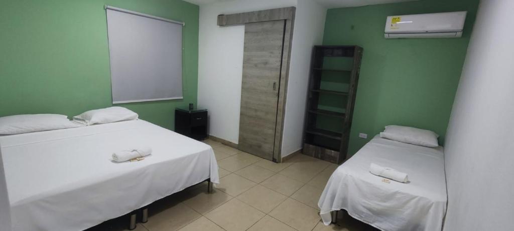 two beds in a room with green walls at Oasis in Valledupar