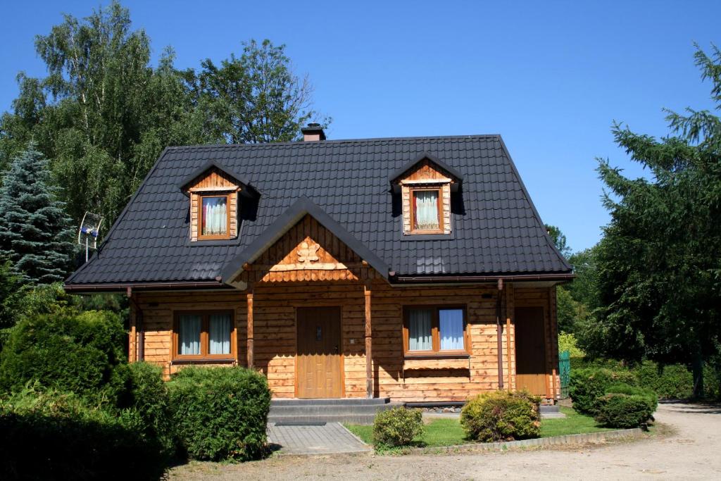a wooden house with a black roof at Domki w Bieszczadach in Polańczyk