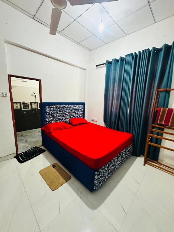 a bedroom with a red bed and blue curtains at G Lake Guest House in Mahiyangana