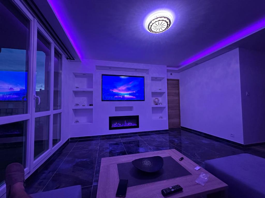 a living room with a tv and purple lighting at Ó maestro home in Avignon