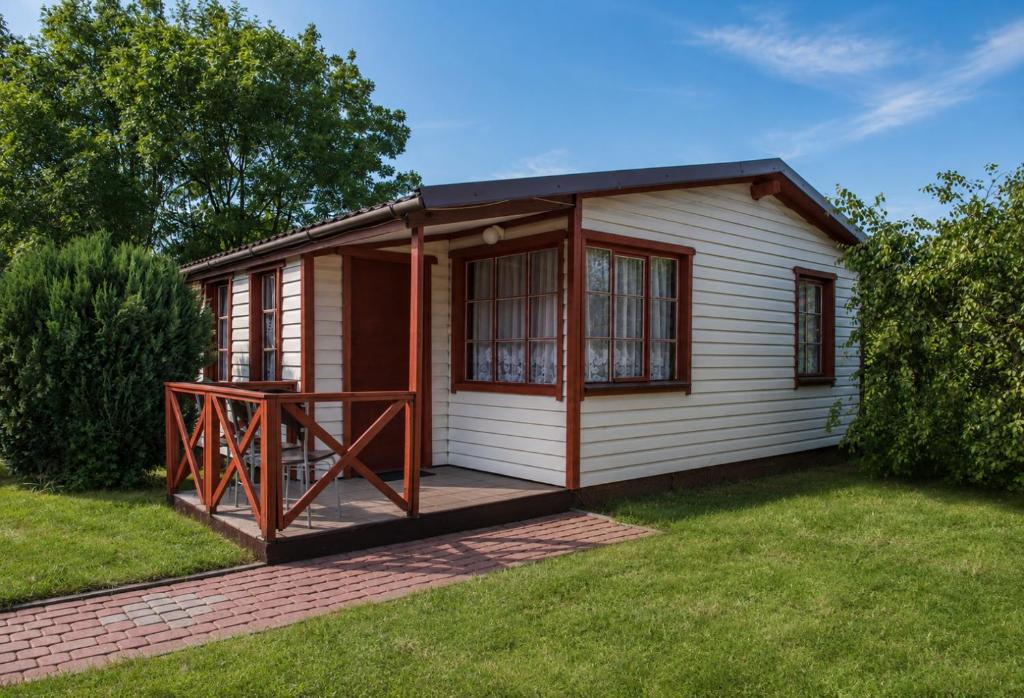 a small cabin with a deck in the grass at Domki Bliźniak in Ustka