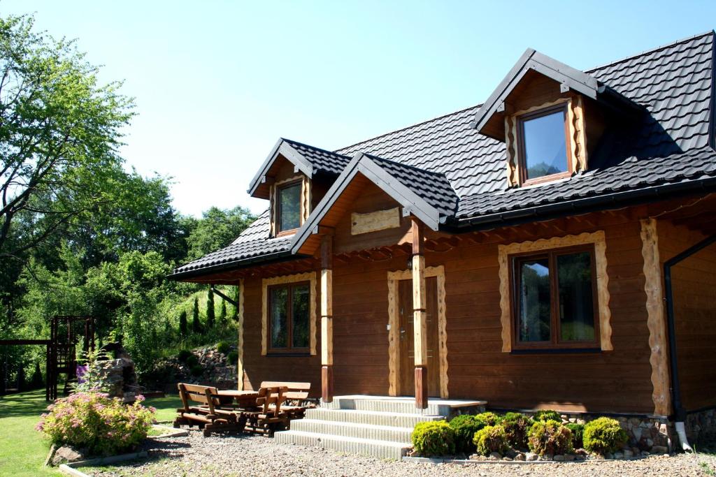 a log cabin with a table and chairs in a yard at Leśny Dworek 1 in Wołkowyja