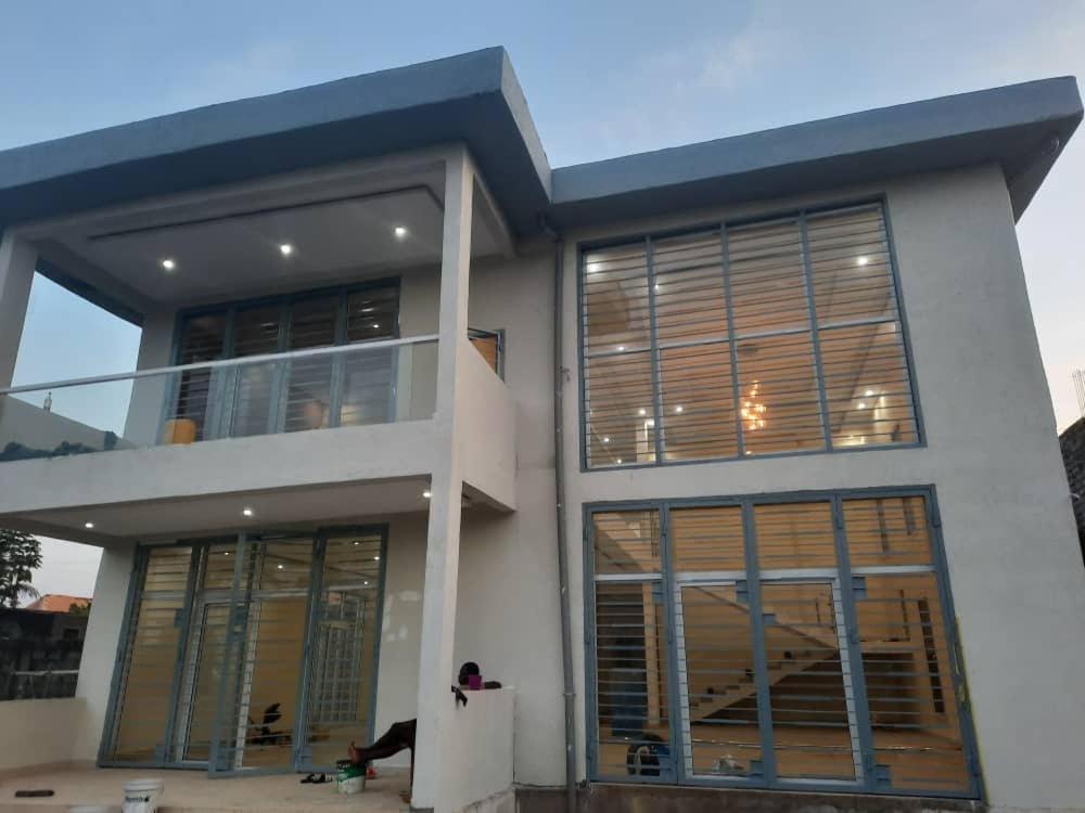 a woman sitting in front of a house at Belle Villa Kassonyah, Conakry in Conakry