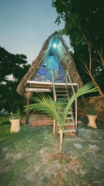 a small hut with a blue umbrella in the grass at Cabana Jamelão in Camaçari