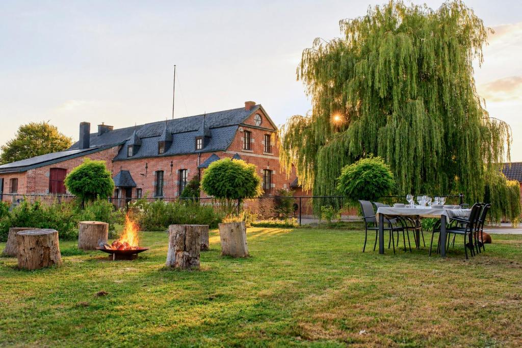 a table and chairs around a campfire in the yard of a house at Les jardins du Quesnoy - 25min de Pairi Daiza in Blicquy