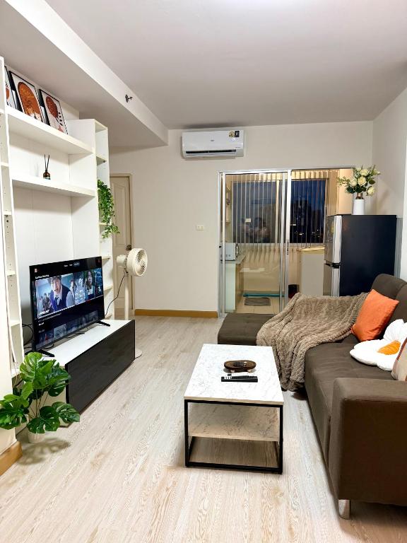 a living room with a couch and a tv at Breezy 1BR Near BTS Udomsuk in Amphoe Phra Khanong