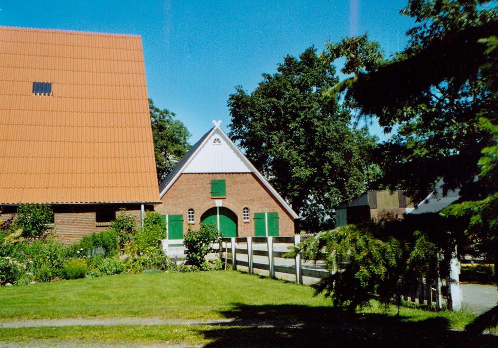 ein Haus mit einem orangenen Dach und einem Zaun in der Unterkunft Ferienhof Lafrenz in Cuxhaven