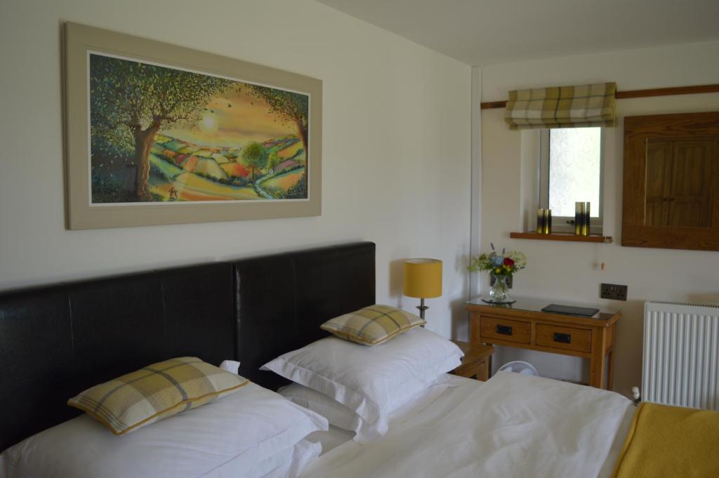 a bedroom with two beds and a painting on the wall at Smithfield Farm Bed & Breakfast in Builth Wells