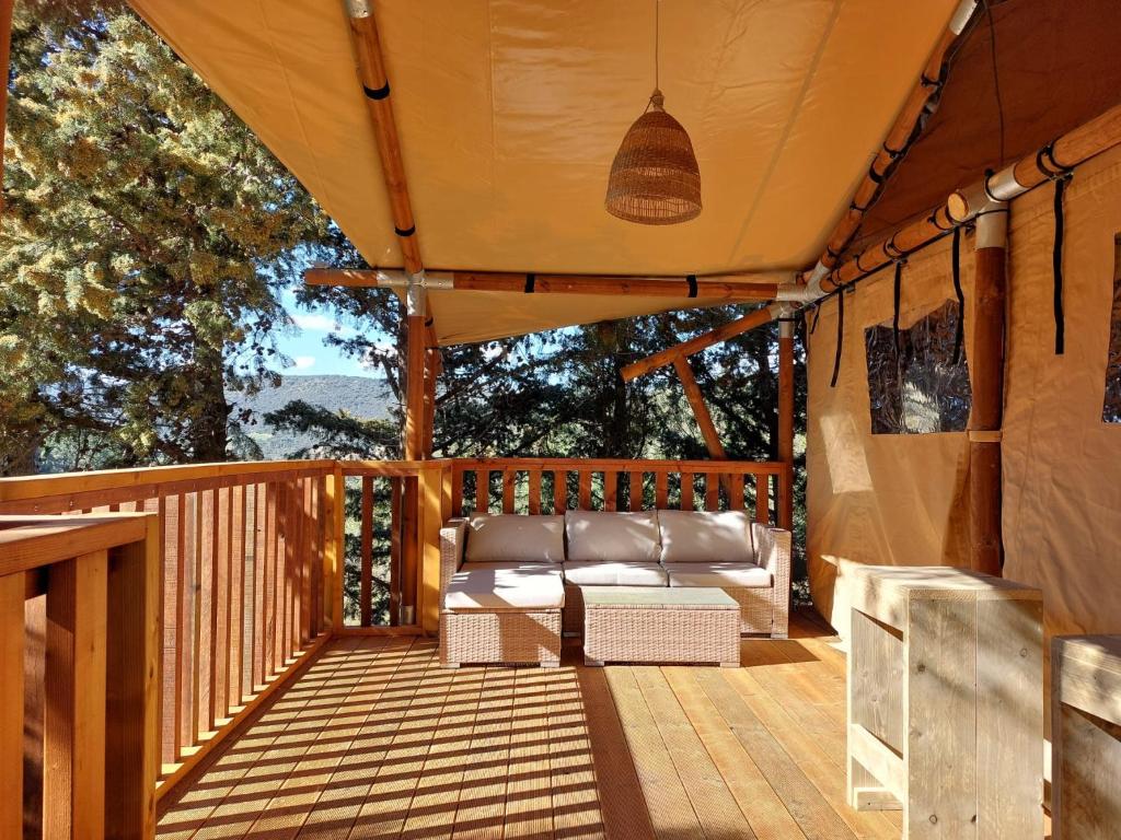 a porch with a couch on a wooden deck at Gîte les 7 saveurs in Cucugnan