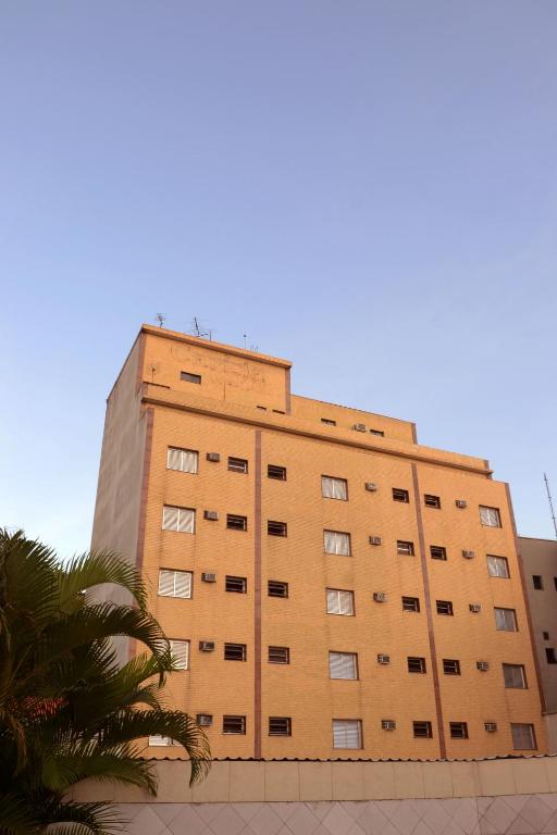 a tall brown building with a palm tree in front of it at Império Hotel in Santos