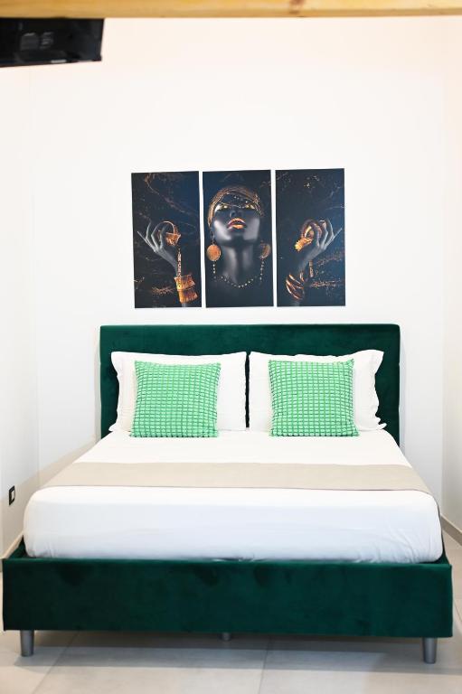a bed with green and white pillows in a room at Victry's Houses Chiaia in Naples