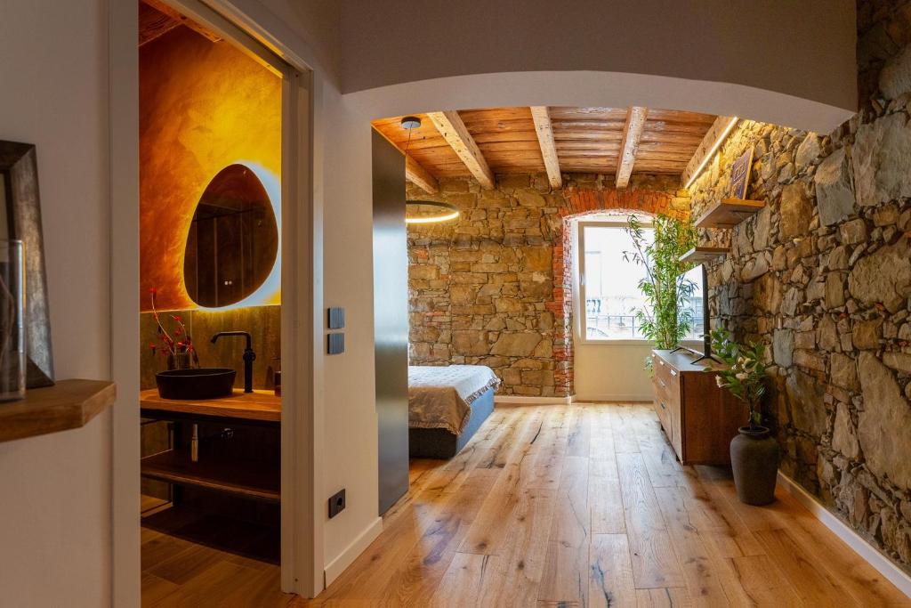 a room with a bed and a stone wall at Stevoski Rooms - Modern Comfort in a Historic Stone House in Cormòns