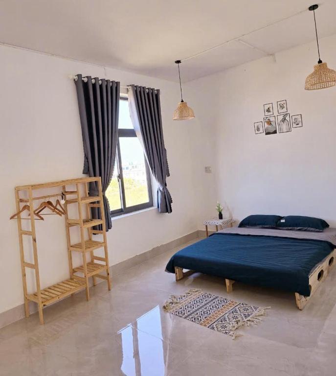 a bedroom with a bed with a blue sheets and a window at Nhi Homestay Phòng đơn 1 in Rạch Giá