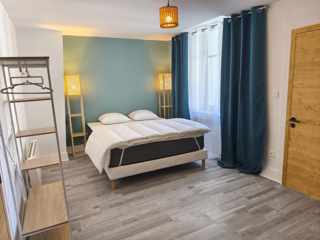 a bedroom with a bed with blue curtains and a mirror at NEW! Appartement PrixMalin 1 à 7 personnes in Champagnole