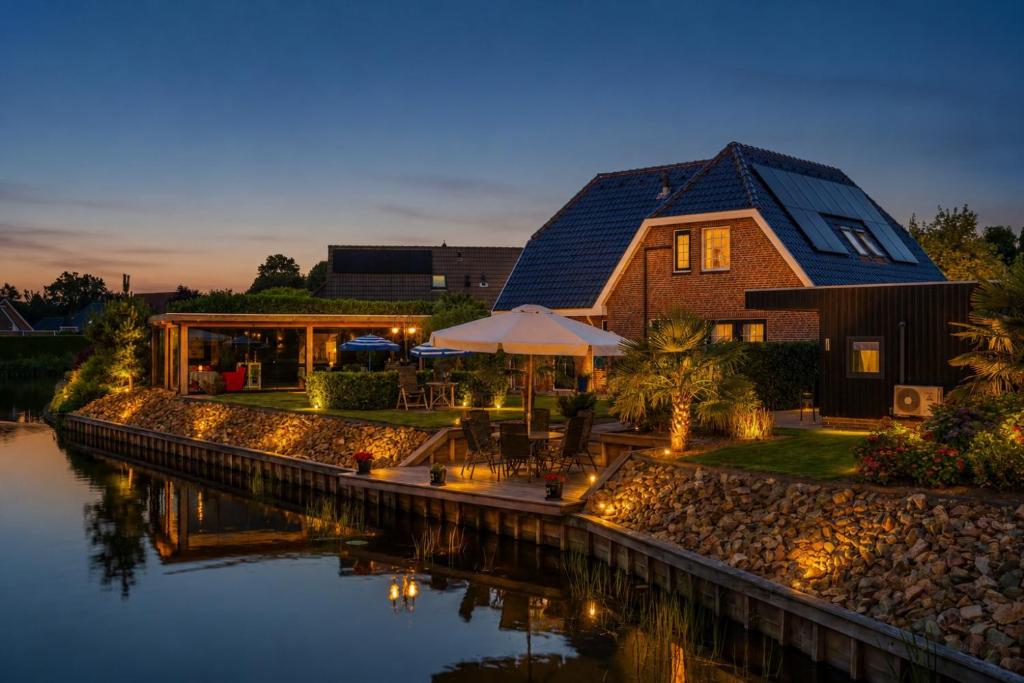 a house by the water at night at B&B de Wiekeborg in Oude Pekela