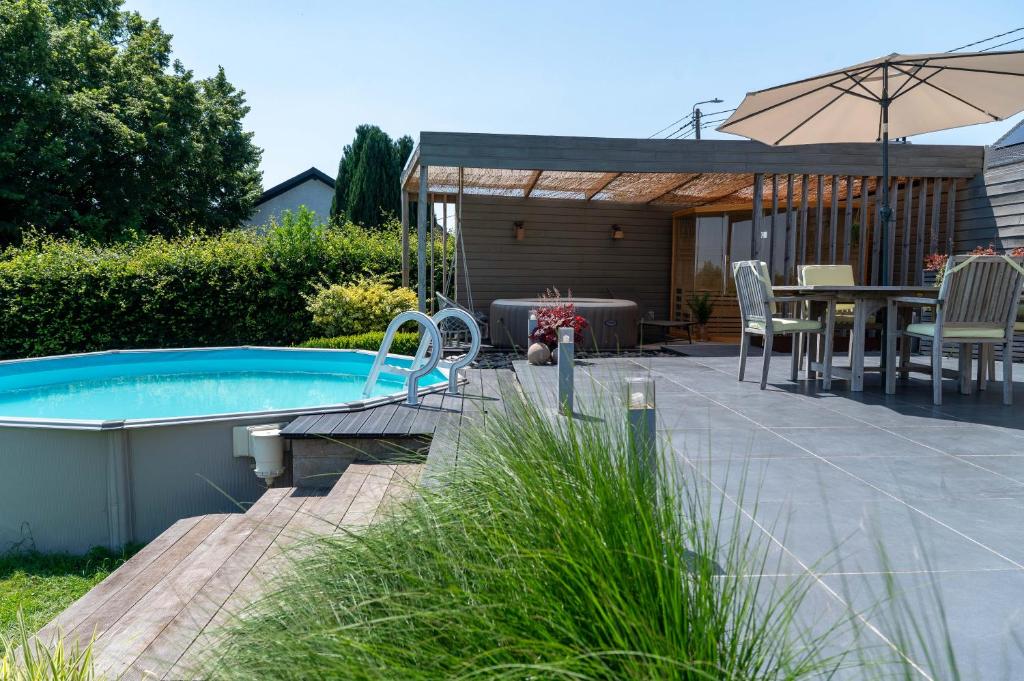 a backyard with a swimming pool and a table and an umbrella at Gîte d'Anpa in Ohey