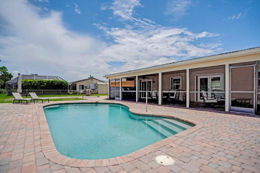 a swimming pool in front of a house at 3BR Pool Villa on Golf Course Huge Yard & Games in Wellington