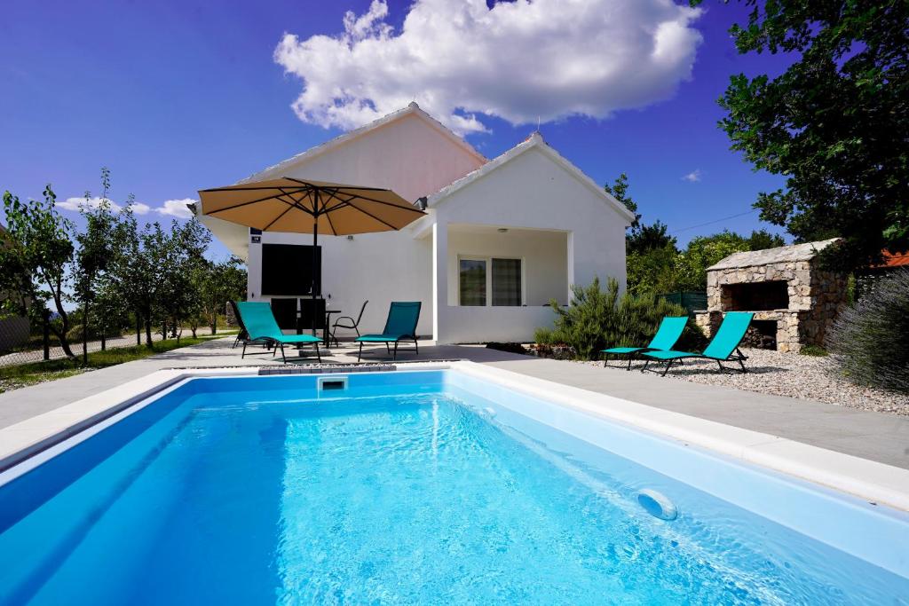 a pool with chairs and an umbrella in front of a house at Villa Dalmatina in Vedrine