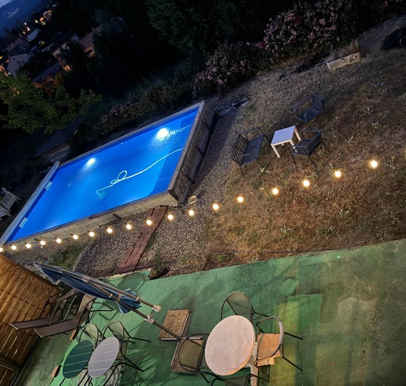 a swimming pool with chairs and an umbrella and lights at Bellavita in Courpière
