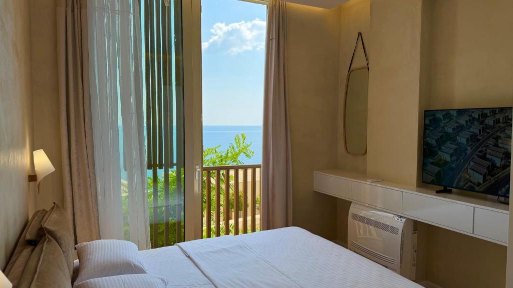 a bedroom with a window with a view of the ocean at Green Coast Pearl Suites Apartments Palase in Palasë