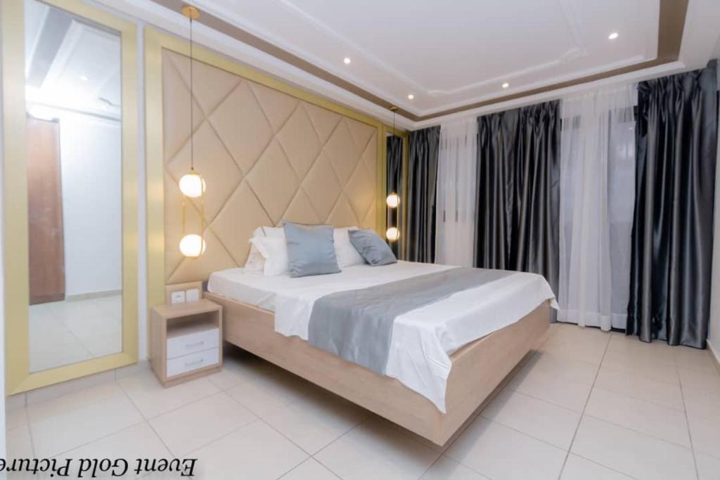 a bedroom with a large bed with blue pillows at Etienne Gae 2 in Douala