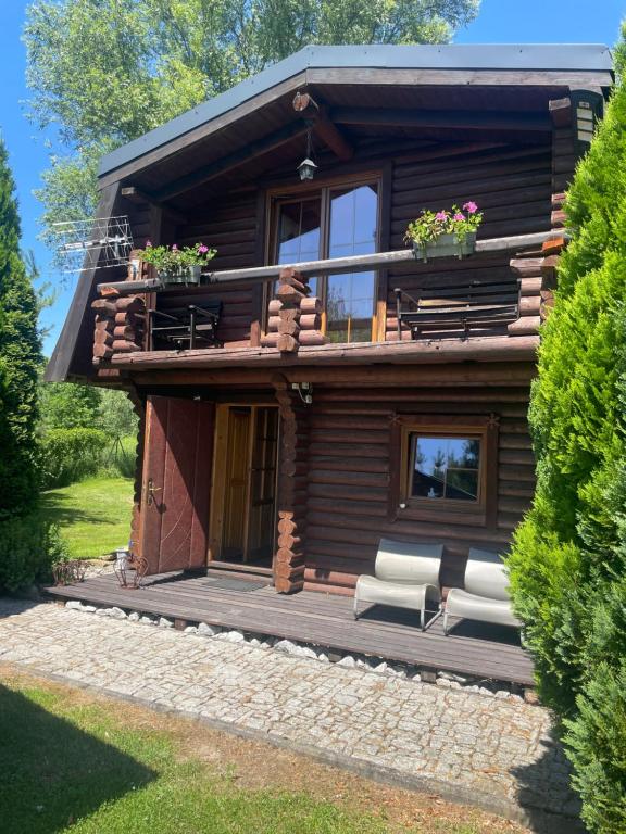 a log cabin with a porch and a balcony at Domek z bali in Wojcieszyce