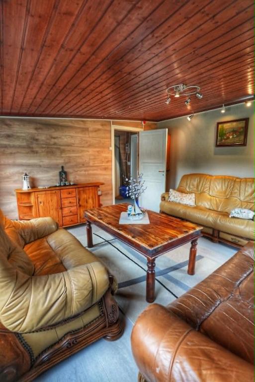 a living room with leather furniture and a wooden ceiling at Lille Ro in Giskemo