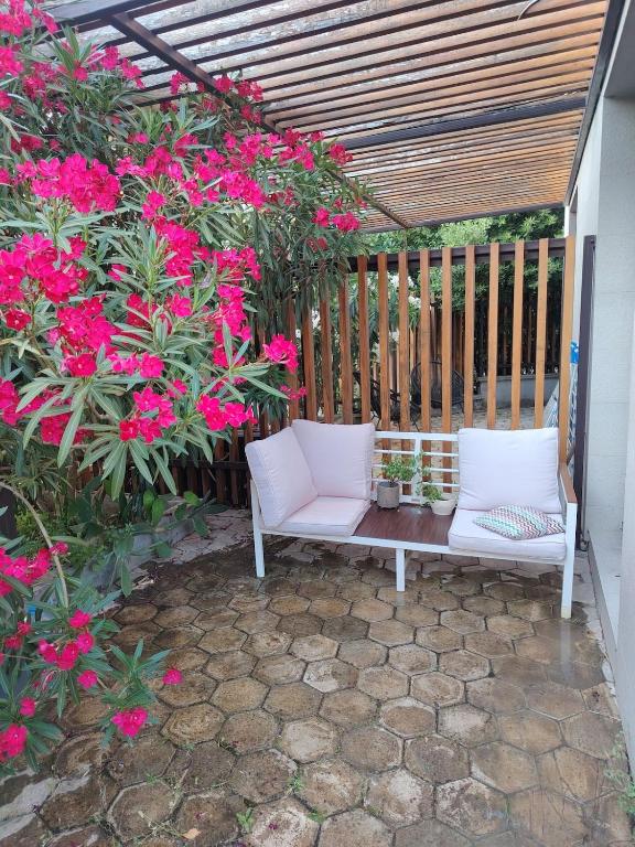 a white bench sitting on a patio with pink flowers at Mini Condos 2 Studio-Loft with garden in Mrčevac