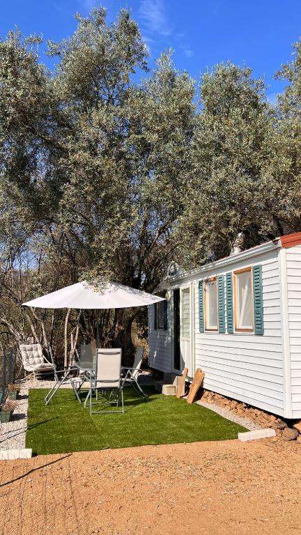 a patio with an umbrella and chairs and a house at Les 3oliviers in Santa-Maria-Siché