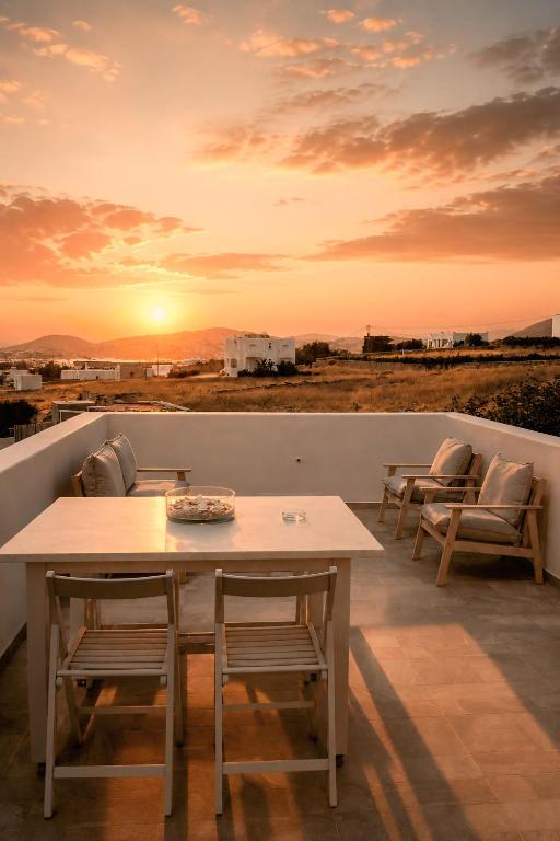 a table and chairs on a balcony with a sunset at Orion Sea View Studio in Parasporos