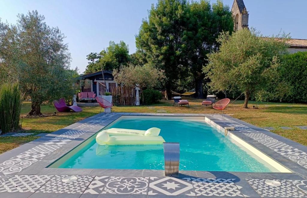 a swimming pool with a chair in a yard at Cabane romantique climatisée avec piscine en pleine nature in Montignac