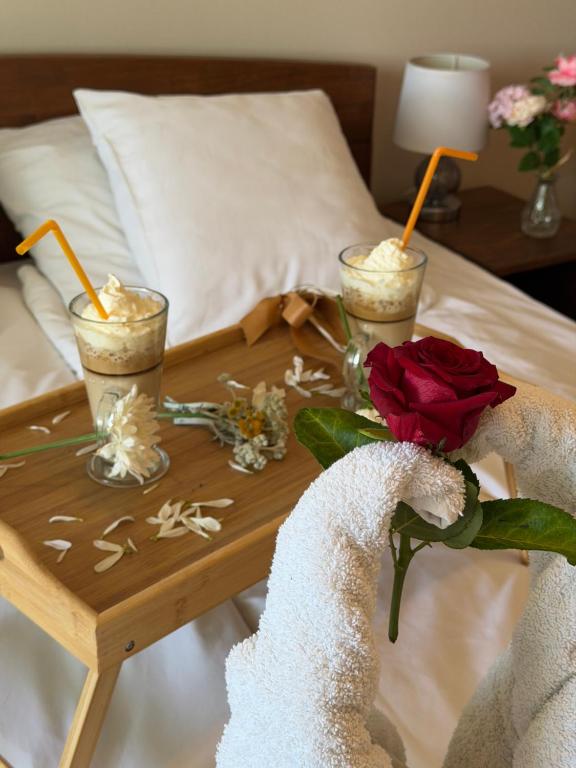 a coffee table with two cocktails and a rose on a bed at Balkan 024 in Subotica