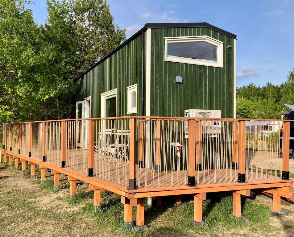 a green tiny house with a wooden deck at Fuchs und Igel Tiny House - Tiny House Fuchs in Möllensee