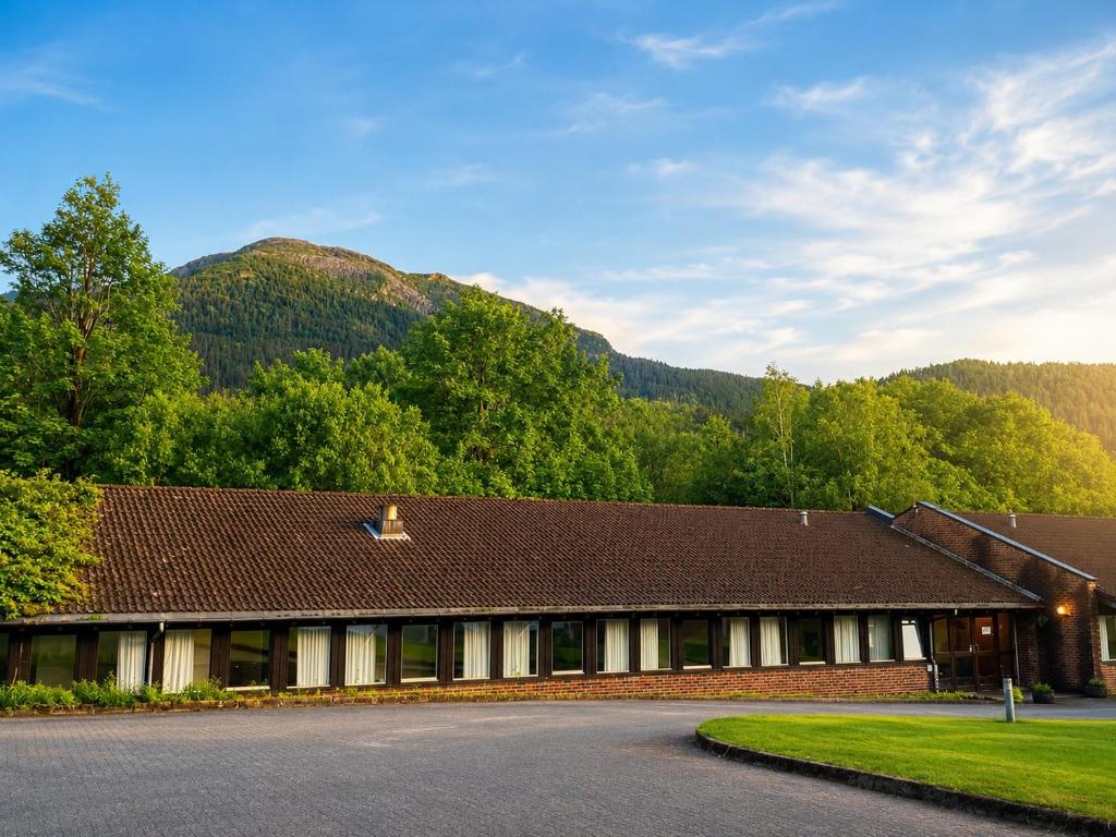 a building with a mountain in the background at Lindum Hotell in Suldalsosen