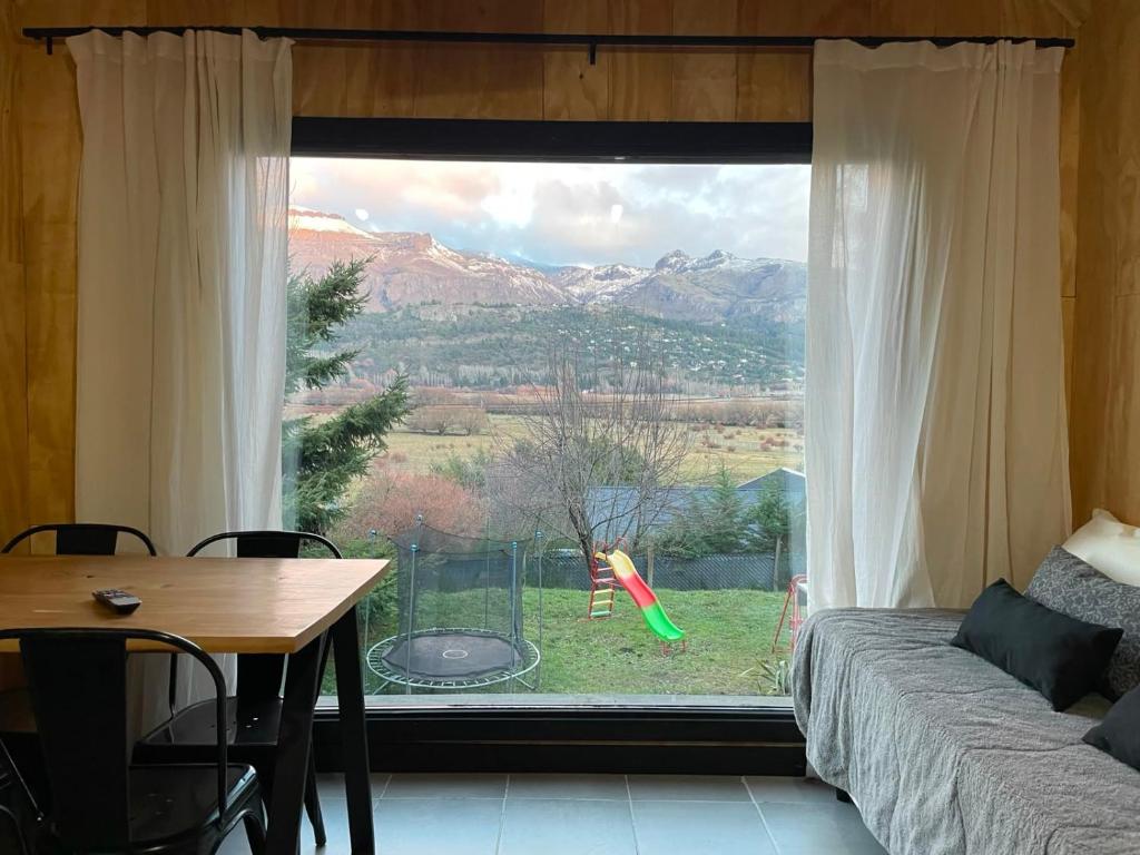 a living room with a table and a large window at cabaña wooden in San Martín de los Andes