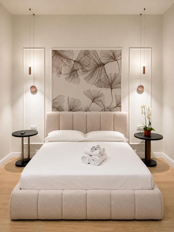 a bedroom with a large white bed with two tables at Xenia Suites Duomo in Reggio di Calabria