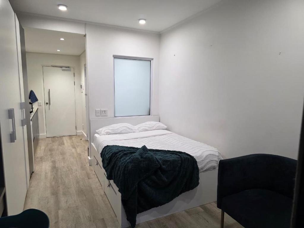 a white bedroom with a bed and a window at Kingsley at 1 on Albert in Cape Town