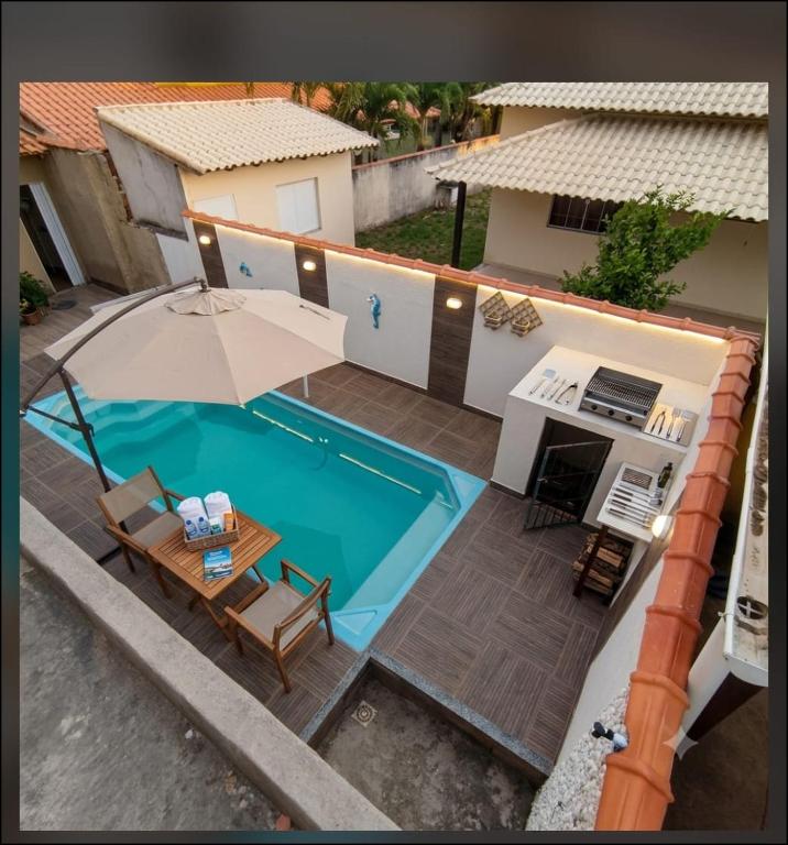 an overhead view of a swimming pool with a table and an umbrella at Casa com piscina e área gourmet próximo à praia com quarto suíte privativo in Saquarema