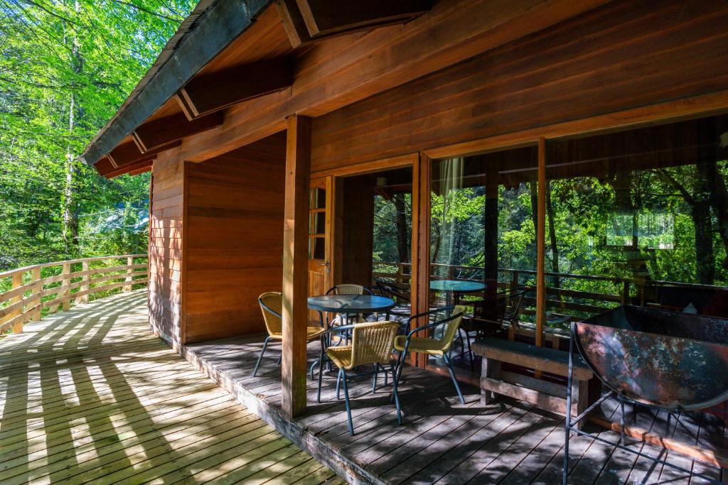 a porch of a cabin with tables and chairs at Patagonia Mawida in Neltume