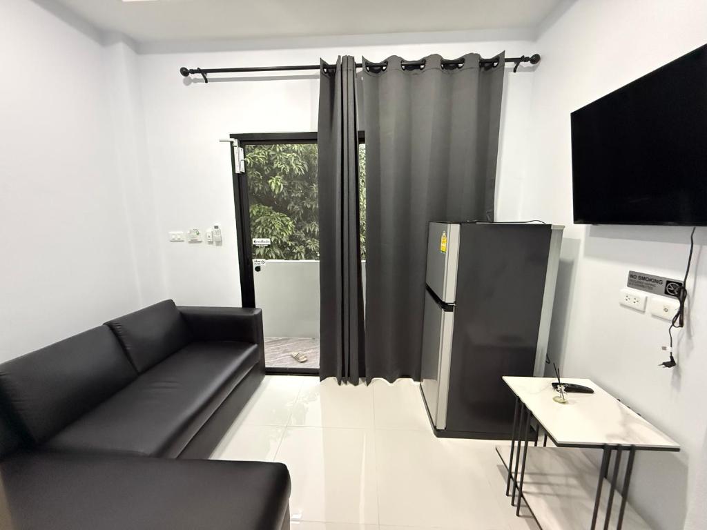 a living room with a black couch and a sliding glass door at Hana residence Bangtao BeachBangtao 11 Phuket in Ban Thalat Choeng Thale