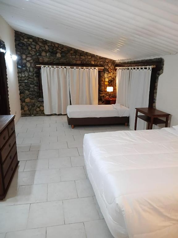 a bedroom with two beds and a stone wall at Aurum patagonia hotel in Lago Puelo