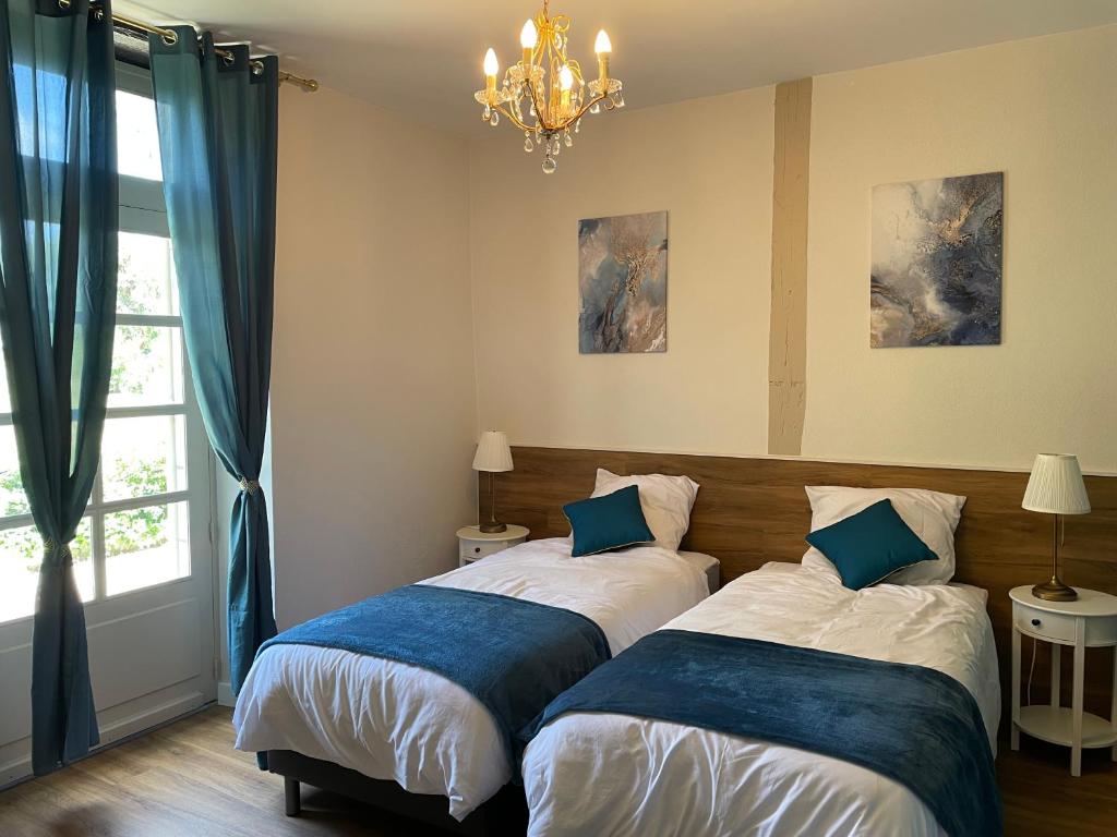 a bedroom with two beds and a chandelier at La Raimbauderie, villa 4 étoiles, avec clim, au coeur de la nature et des vignobles in La Chapelle-Montlinard