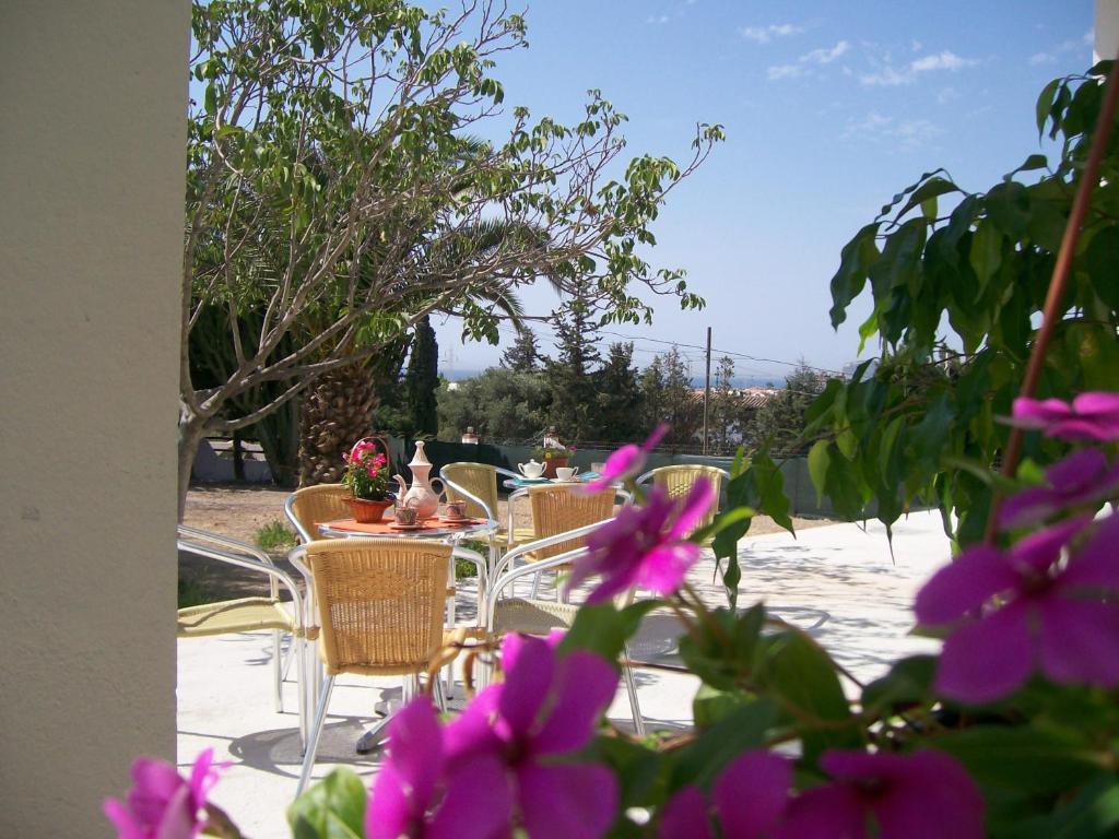 un patio con tavoli, sedie e fiori viola di Belvedere Sul Mare a Quartu SantʼElena