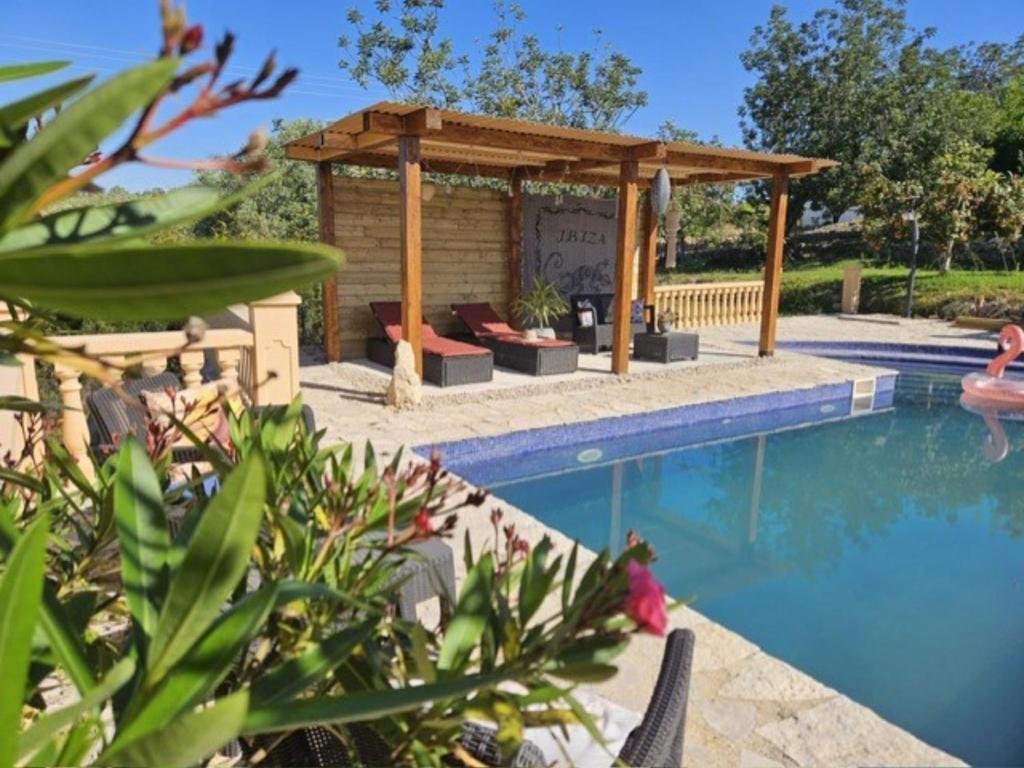 a swimming pool with a gazebo next to a swimming pool at Vila Girasoles in Cálig