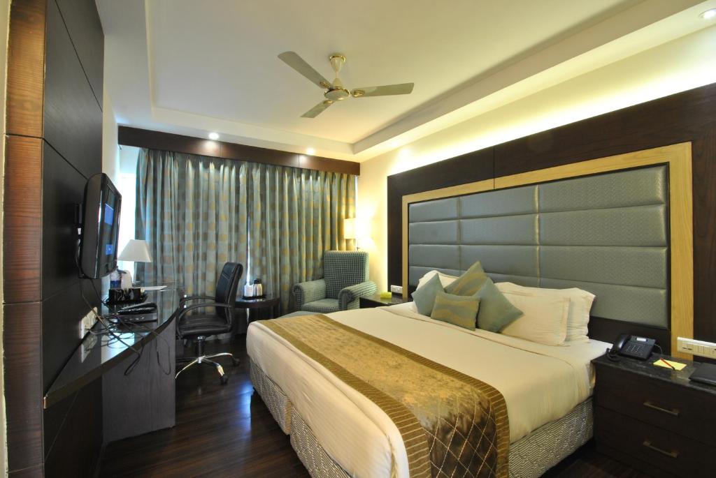 a hotel room with a large bed and a desk at Hotel Royal Cliff in Kānpur