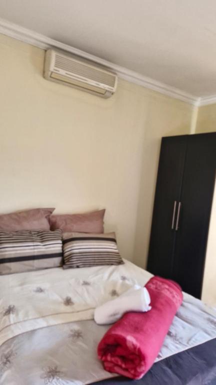 a bedroom with a bed with a red blanket on it at Self Contained Batchelor pad in Germiston