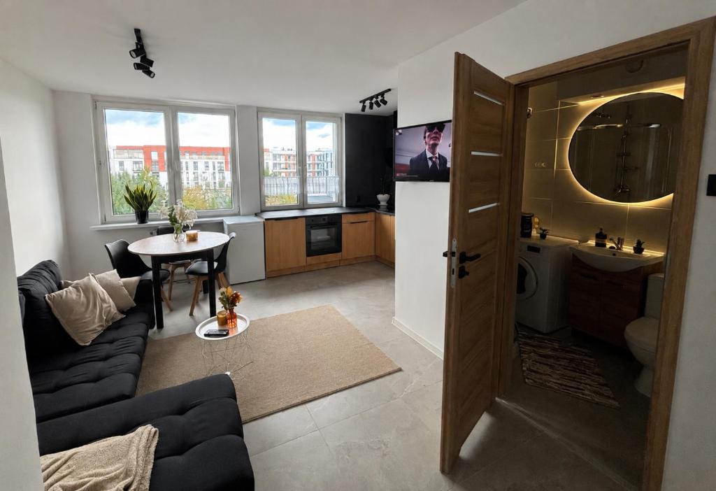a living room with a table and a kitchen at Apartament w Centrum Miasta in Brodnica