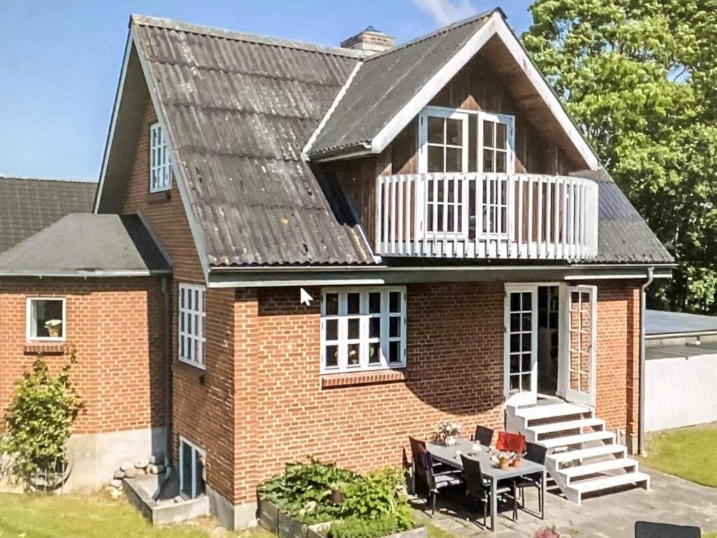 a brick house with a balcony and a table at Unique Coastal Retreat - By Traum Ferienwohnungen in Hadsund